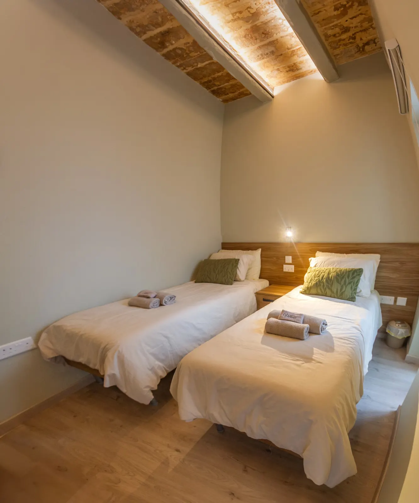 Twin beds under a lit timber ceiling